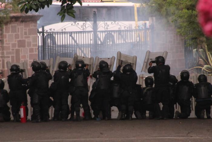 Comuneros de Arantepacua se enfrentan con antimotines en Casa Michoacán; bloquean libramiento y prenden pastizal